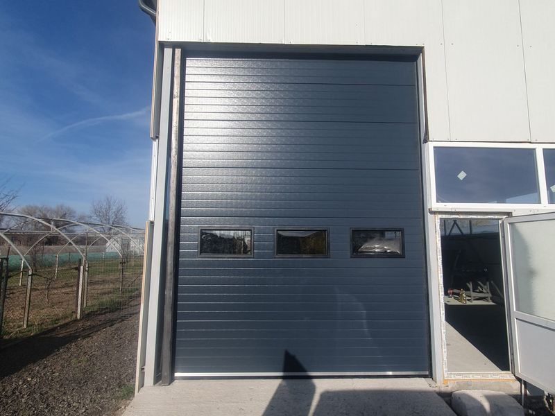 Ușă industrială secțională antracit RAL 7016 montată la o hală în județul Brașov